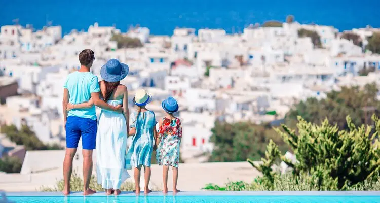 Family of four on european vacation on the edge of pool in Mykonos, Greece
