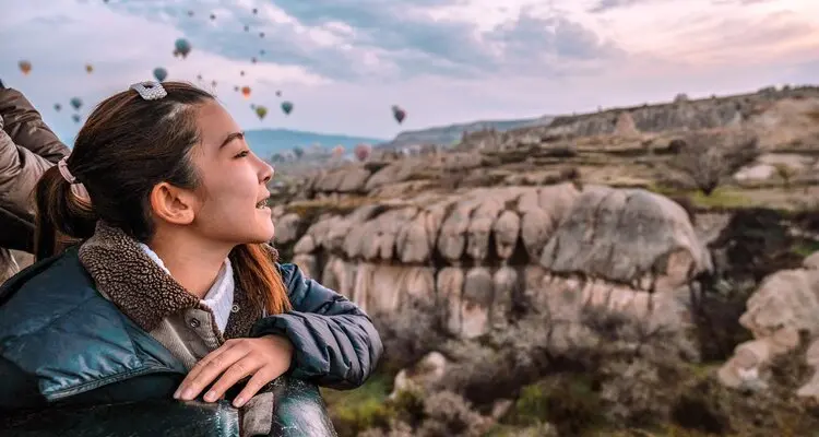 woman watching colorful hot air balloons flying over the valley at Cappadocia, Turkey