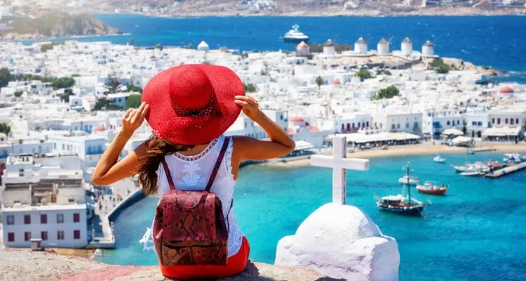 enjoys the view over the town of Mykonos island, Cyclades, Greece