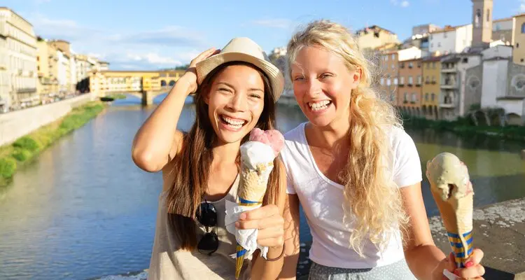 Happy women friends eating ice cream in Florence